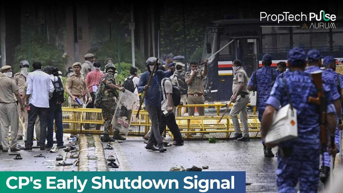 Security personnel and police deployed behind barricades on a rain-soaked Delhi street amid civil unrest, with debris scattered across the road and emergency response vehicles in the background